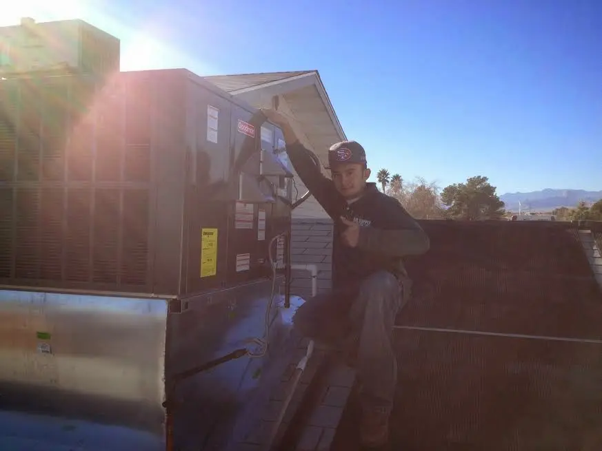 HVAC technician performing Air Duct Repair on a rooftop unit in Ada